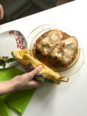 Kıyma hazırlanması alır. Kadın onun elinde bir tabak hazır tavuk rulo tutuyor.