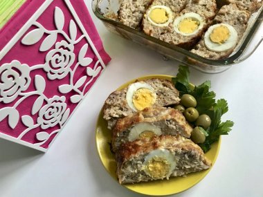 Kıyma hazırlanması alır. Yumurta haşlanmış bir dolgu olarak. Zeytin ve yeşillik ile bir tabakta bitmiş rulo dilim vardır.