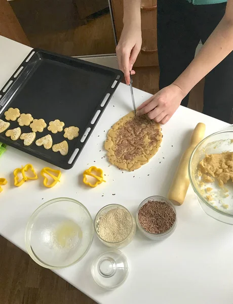 Preparación de pasteles caseros. En la mesa hay harina, mantequilla, bandeja para hornear y formas para la masa. Vista desde arriba. Una mujer saca la pasta. Hay una masa en la mesa, una bandeja para hornear con b —  Fotos de Stock