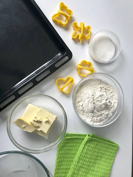 Preparación de pasteles caseros. En la mesa hay harina, mantequilla, bandeja para hornear y formas para la masa. Vista desde arriba . —  Fotos de Stock