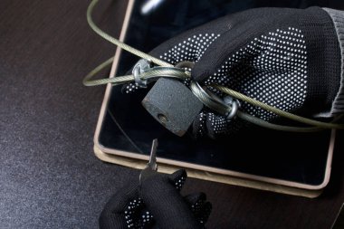Bilgisayar güvenliği. Verilere erişimin korunması. Tablet bir güvenlik kablosu ve bir kilit tarafından korunmaktadır. Kilidi açmak ve bilgisayara erişmek bir saldırgan eldiven ile çalışır.