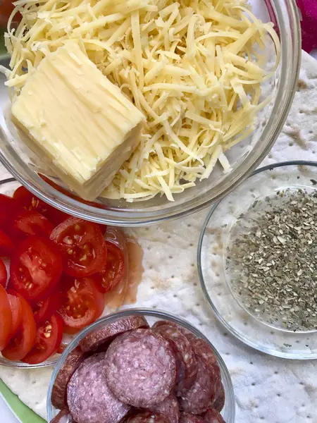 Приготування піци. Необхідні інгредієнти на столі: сир, ковбаса, база піци та овочі . — стокове фото
