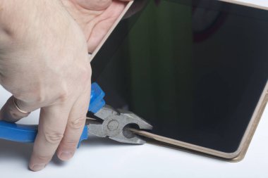 Tablet ve çalışma araçları. Beyaz tablo üzerinde bir tablet, skein, keski ve pense yüzeydir. Yıkım ve elektronik cihazların tamiri.