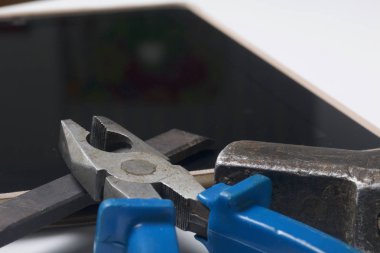 Tablet ve çalışma araçları. Beyaz tablo üzerinde bir tablet, skein, keski ve pense yüzeydir. Yıkım ve elektronik cihazların tamiri.