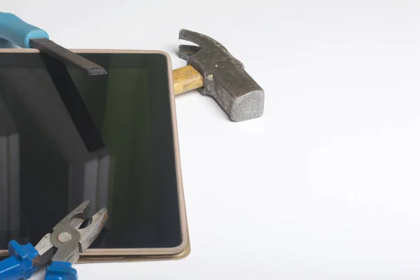 Tabletu a pracovní nástroje. Na bílém povrchu stolu je tablet, přadena, dláto a kleště. Zničení a opravy elektronických zařízení. — Stock fotografie