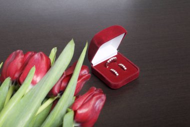 Sevdikleriniz için hediyeler. Bir demet kırmızı lale. Yakın olan bir yüzük ve küpeler ile bir kırmızı kadife kutu.