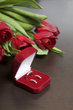 Sevdikleriniz için hediyeler. Bir demet kırmızı lale. Yakın olan bir yüzük ve küpeler ile bir kırmızı kadife kutu.