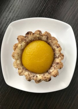 Bir kayısı dolgulu kek üzerinde beyaz bir daire yer almaktadır. Karanlık bir arka plan üzerinde.