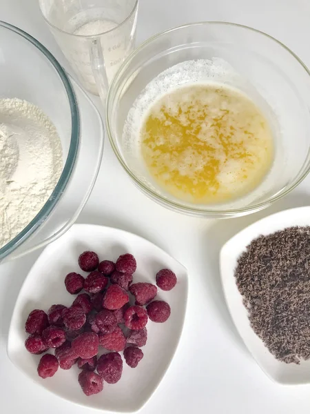 Ingredientes para la preparación de masa pastelera: harina, ghee, chocolate rallado y frambuesa. Vista desde arriba. Sobre un fondo blanco . — Foto de Stock