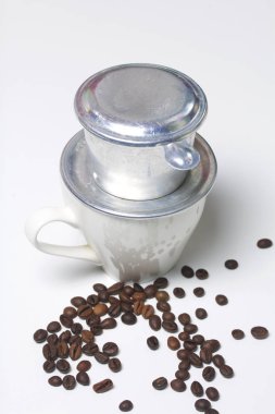 Kahve monte formundaki için Vietnamca brewer beyaz bir bardakta duruyor. Sonraki dağınık kahve çekirdekleri.