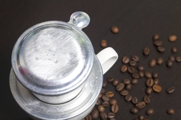 El cervecero vietnamita para el café en forma ensamblada está de pie en una taza blanca. Siguiente granos de café dispersos . — Foto de Stock