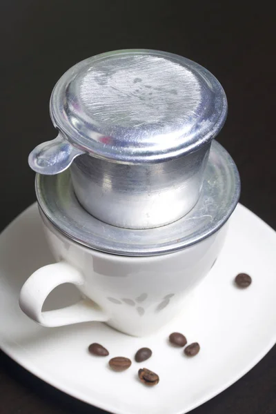 Vietnamese coffee maker is equipped on a cup. It is filled with ground coffee and pour boiling water.