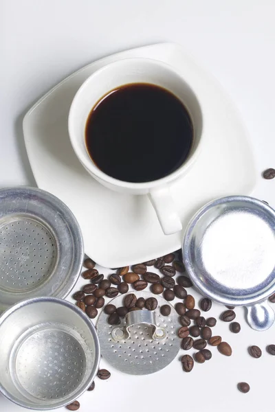 Una taza de café está en el platillo. La tetera vietnamita para el café en forma desmontada se encuentra en una superficie. Siguiente granos de café dispersos . — Foto de Stock
