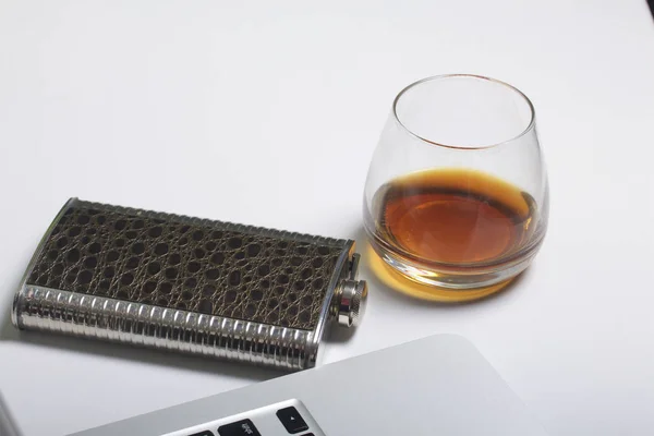 Whiskey in a glass and a flask. Nearby is a laptop. Rest of the day off. — Stock Photo, Image