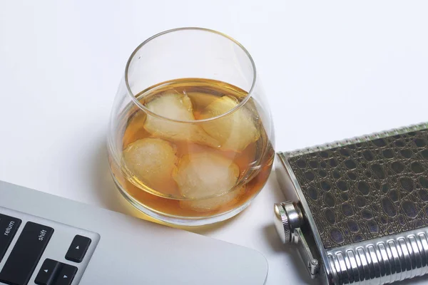 Whiskey with ice in a glass and a flask. Nearby is a laptop. Rest of the day off. — Stock Photo, Image