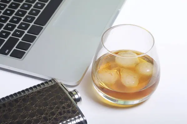 Whiskey with ice in a glass and a flask. Nearby is a laptop. Rest of the day off. — Stock Photo, Image