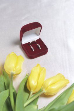 Sevdikleriniz için hediyeler. Bir buket Sarı laleler ışık bir yüzeye dağınık olduğunu. Yakınlarda bir açık kadife kırmızı renk altın süslemeli kutun.