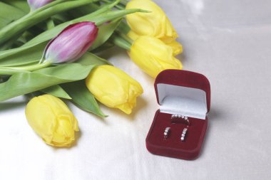 Sevdikleriniz için hediyeler. Bir buket sarı ve Pembe Lale ışık bir yüzeye dağınık olduğunu. Yakınlarda bir açık kadife kırmızı renk ile altın takı kutun.