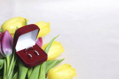 Sevdikleriniz için hediyeler. Bir buket sarı ve Pembe Lale ışık bir yüzeye dağınık olduğunu. Yakınlarda bir açık kadife kırmızı renk ile altın takı kutun.