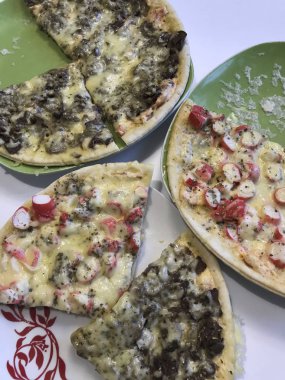 Masada iki taze hazırlanmış pizza vardır. Mantar, diğer Yengeç ile bir sopa. Her ikisi de eritilmiş peynir kalın bir tabaka ile kaplıdır.