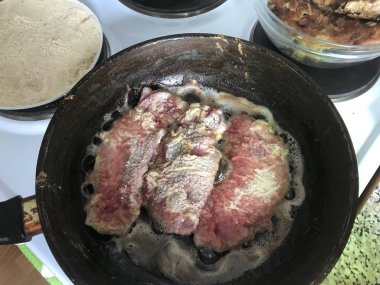 Sıcak bir tavada et parçaları yanmış. Sıcak yağ sıçraması vardır.