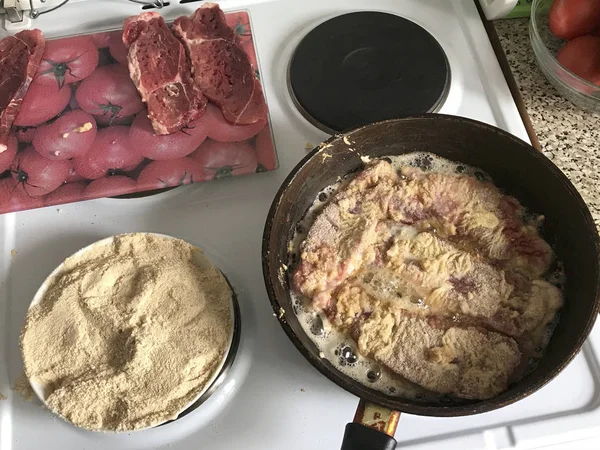 Bitar av kött är stekt i en het stekpanna. Det finns stänk av hett fett. — Stockfoto