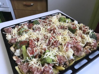 Dilimlenmiş patates ve mantar kavurma fırında için pişirme tepsiye koyulur. Eklenen onları kıyılmış et, karnabahar ve baharat. Her şeyi rendelenmiş peynir tabakası ile serpilir.