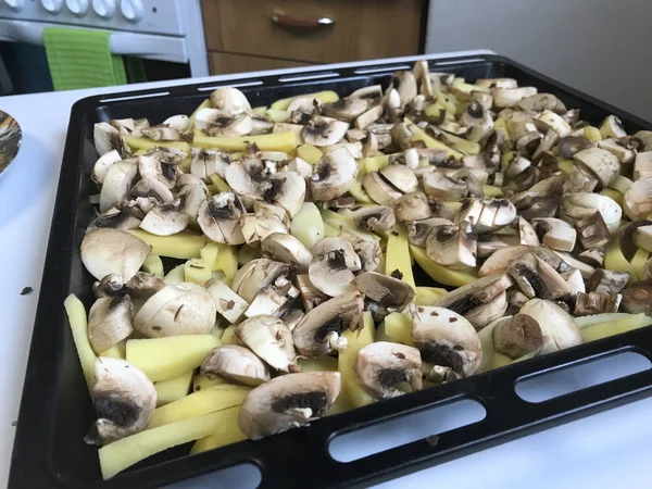 Нарізану картоплю і гриби для обсмажування в духовці кладуть на випічку . — стокове фото
