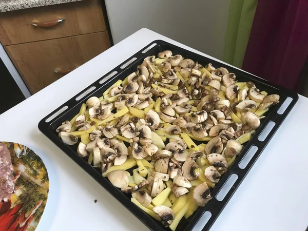 Papas en rodajas y setas para asar en el horno se colocan en la bandeja de hornear . —  Fotos de Stock