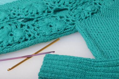 Zümrüt rengi ve kanca için örgü örgü için iş parçacığı dizeleri. Hazır bir örme ürün üzerinde yalan.