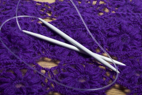 Haken zum Stricken vor dem Hintergrund einer gestrickten violetten Handtasche. — Stockfoto