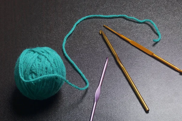 Změť vláken pro pletení smaragdové barvy a háčky na pletení na tmavém pozadí. — Stock fotografie