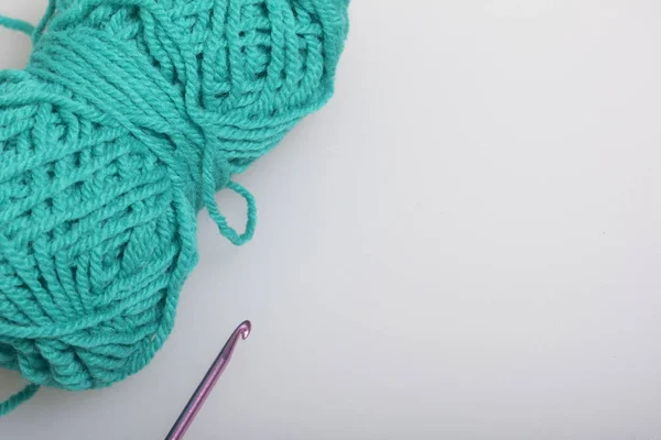Změť vláken pro pletení smaragdové barvy a háčky na pletení na bílém pozadí. — Stock fotografie