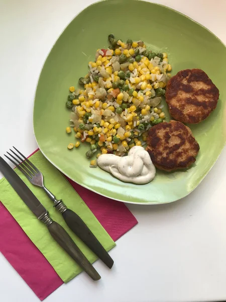 Las croquetas fritas de la carne de salmón y hortalizas con la salsa se acuestan en el plato. Hay cubiertos cerca. . —  Fotos de Stock