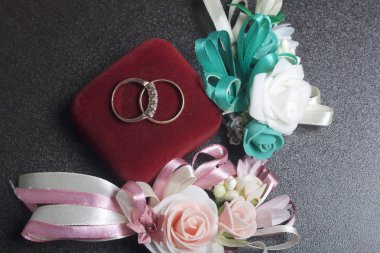 Dekor düğün. Alyans karanlık yüzeyinde yalan. Gelin ve damat yaka çiçeği yakınlarda bulunmaktadır.