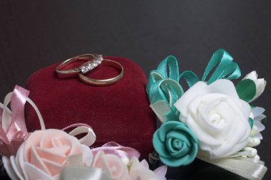 Dekor düğün. Alyans karanlık yüzeyinde yalan. Gelin ve damat yaka çiçeği yakınlarda bulunmaktadır.