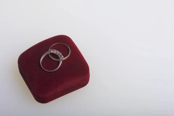 Svatební výzdobu. Snubní prsteny leží na bílém povrchu. Nedaleko jsou boutonniere nevěstu a ženicha. — Stock fotografie