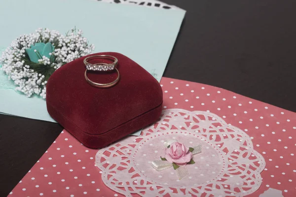 Decoración de la boda. Tarjetas de invitación y anillos de boda en una caja, se encuentran en una superficie oscura . — Foto de Stock
