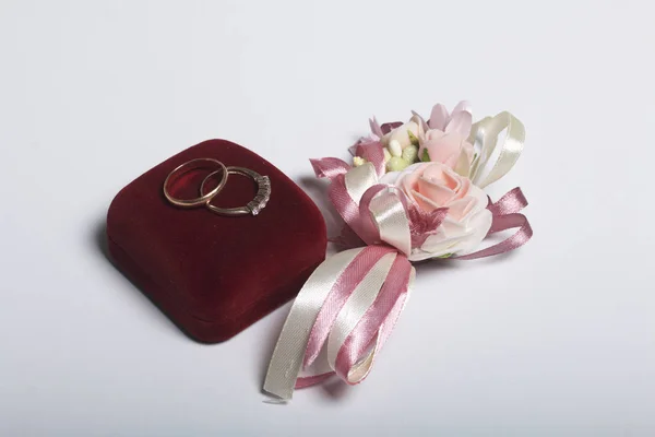 Esküvői dekoráció. Boutonniere menyasszony, az esküvő gyűrű, doboz, feküdjön egy fehér felületre. — Stock Fotó