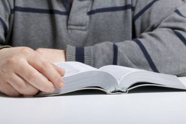 Genç bir adam masada oturan bir gümüş dilim İncil okur.