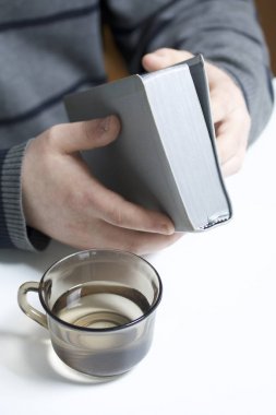 Genç bir adam masada oturan bir gümüş dilim İncil okur. Yanında su ile bir kupa olduğunu.