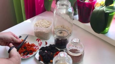 Adam bir karışımı müsli için hazırlanıyor. O makas ile kurutulmuş meyve keser