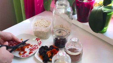 Adam bir karışımı müsli için hazırlanıyor. O makas ile kurutulmuş meyve keser