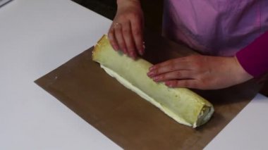 Kadın sünger kek krem yayılır ve bir rulo tamamladı. Bisküvi rulo hazırlanması. Hazırlık aşamaları