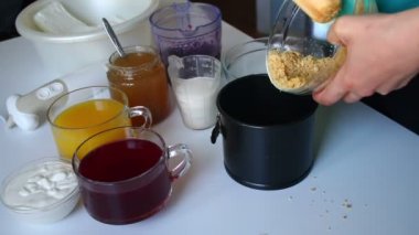 Tatlı hazırlanması. Kadın bir kalıp içine ufalanmış kurabiyeler dökülen ve onları bir oklava ile sıkıştırır. Masaya unsurlarıdır