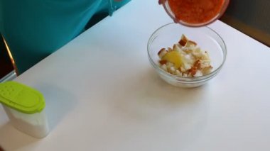 Bir kadın kıyma somon yemek pişiriyor. Bir kaba yumurta ve ezilmiş ekmek ile doğranmış somon eti ekler