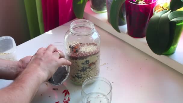 该名男子添加干果的玻璃罐与麦片和混合 — 图库视频影像