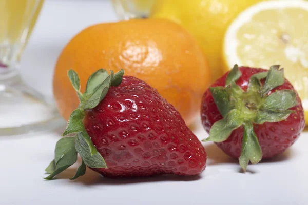 Op tafel ligt fruit en bessen: aardbeien, citroen en Mandarijn. — Stockfoto