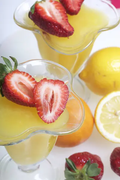 在陶器上的果冻, 用草莓装饰。桌子旁边是水果: 官员, 柠檬和 bayut. — 图库照片