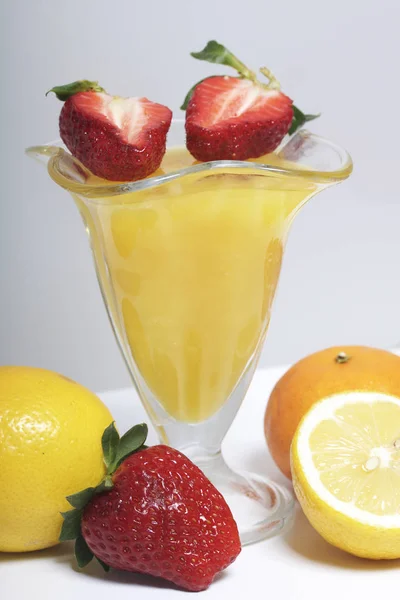 Jelly in de servies, gedecoreerd met aardbeien. Naast de tabel zijn vruchten: mandarijnen, citroen en bayut. — Stockfoto